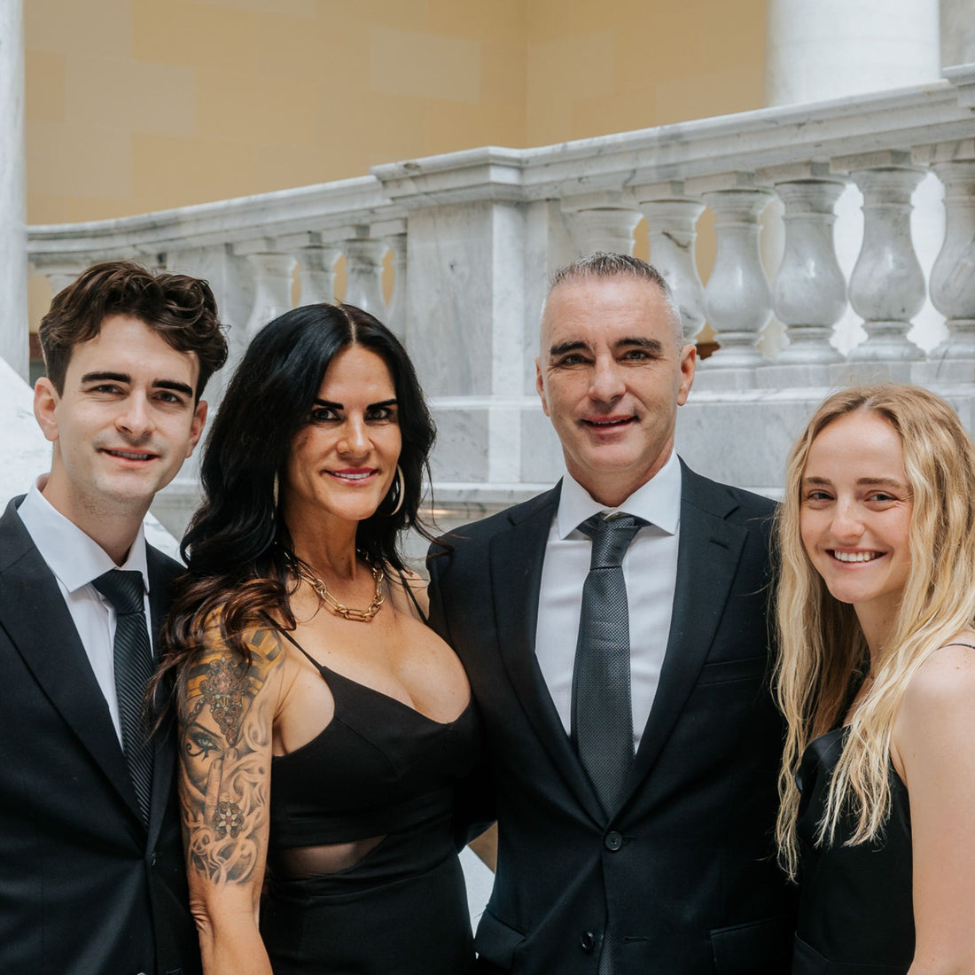 Four people posing for a photo in formal attire against a classical architecture background.