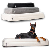 Wasatch Pup Luxury Orthopedic Dog Bed with raised supportive bolsters and a soft bouclé fabric cover. Shown in all three available colors—Charcoal, Grey, and Bone—with a Doberman resting on the Bone bed. The rectangular bolster design provides an open central sleeping area and raised cushioned sides where dogs can rest their heads.